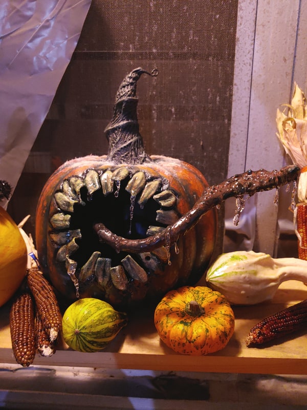 monster pumpkin with wicked tongue carved out of foam and foamclay and dripping in uv resin, surrounded by festive squash and corn